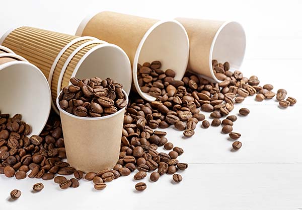 AdobeStock_307610999.jpeg (Paper coffee cups with coffee beans on white table)