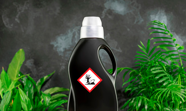 AdobeStock_542741417_redigeret.jpg (Natural laundry detergent mockup for washing black clothes. Washing detergent concept with bottle of washing gel or fabric softener on laundry basket on black background with house plants. Laundry day)