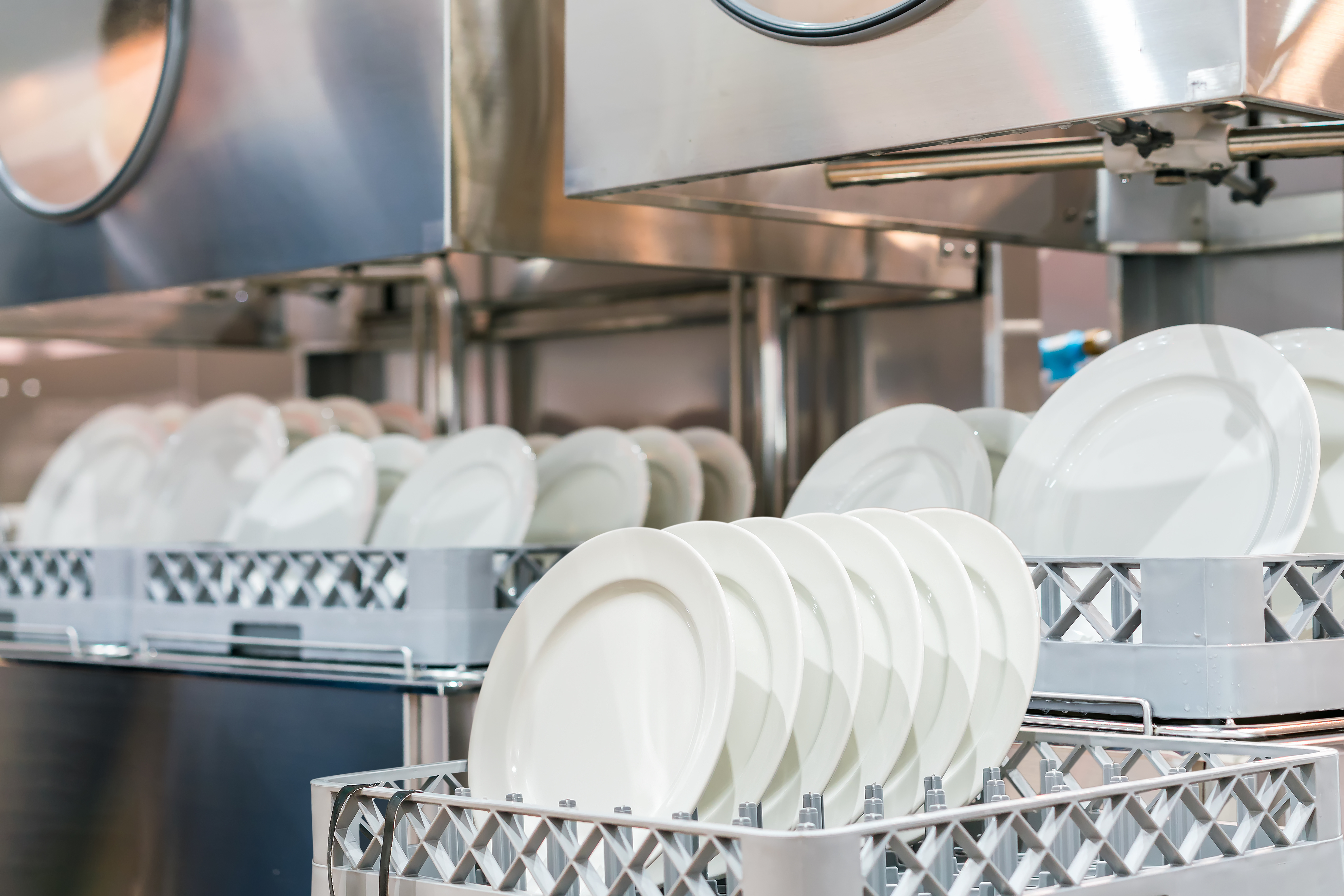 AdobeStock_408369175.jpeg (many dish or white plate arranged on basket for cleaning by automatic dishwasher machine in kitchen room restaurant)
